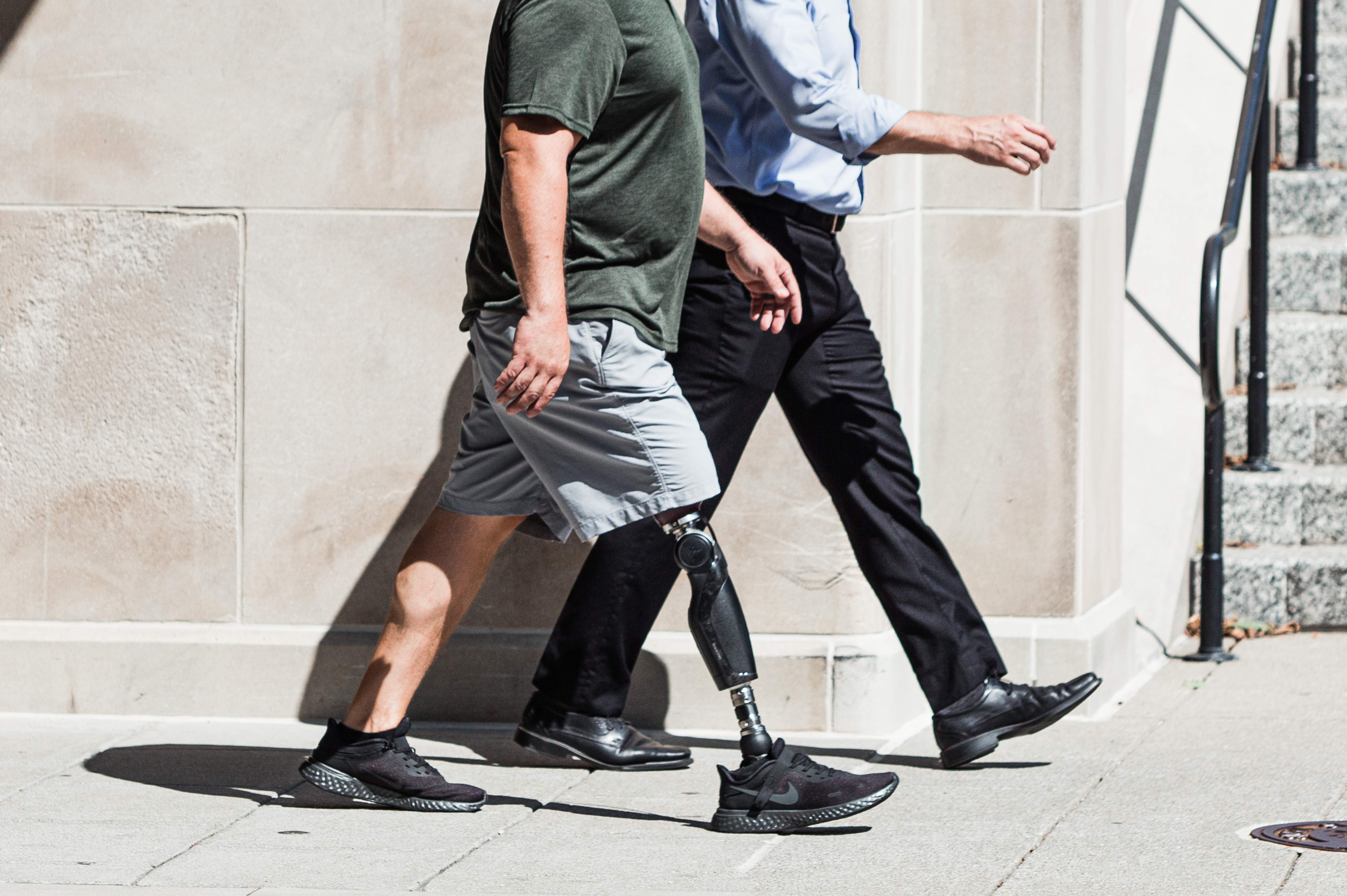 two men walking, one has bionic leg